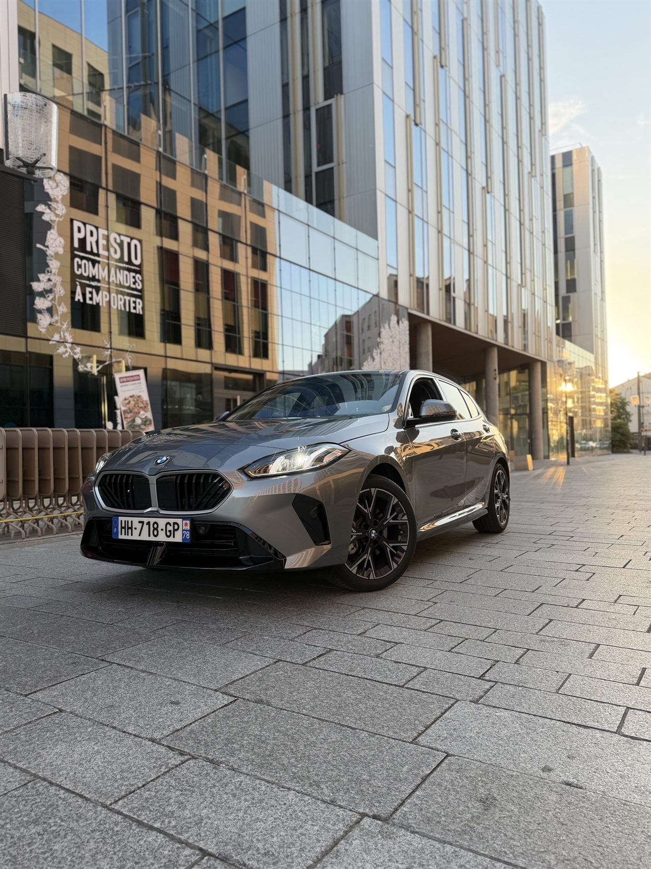 Location de voiture premium à Lyon — BMW 120i M Sport devant un immeuble lyonnais